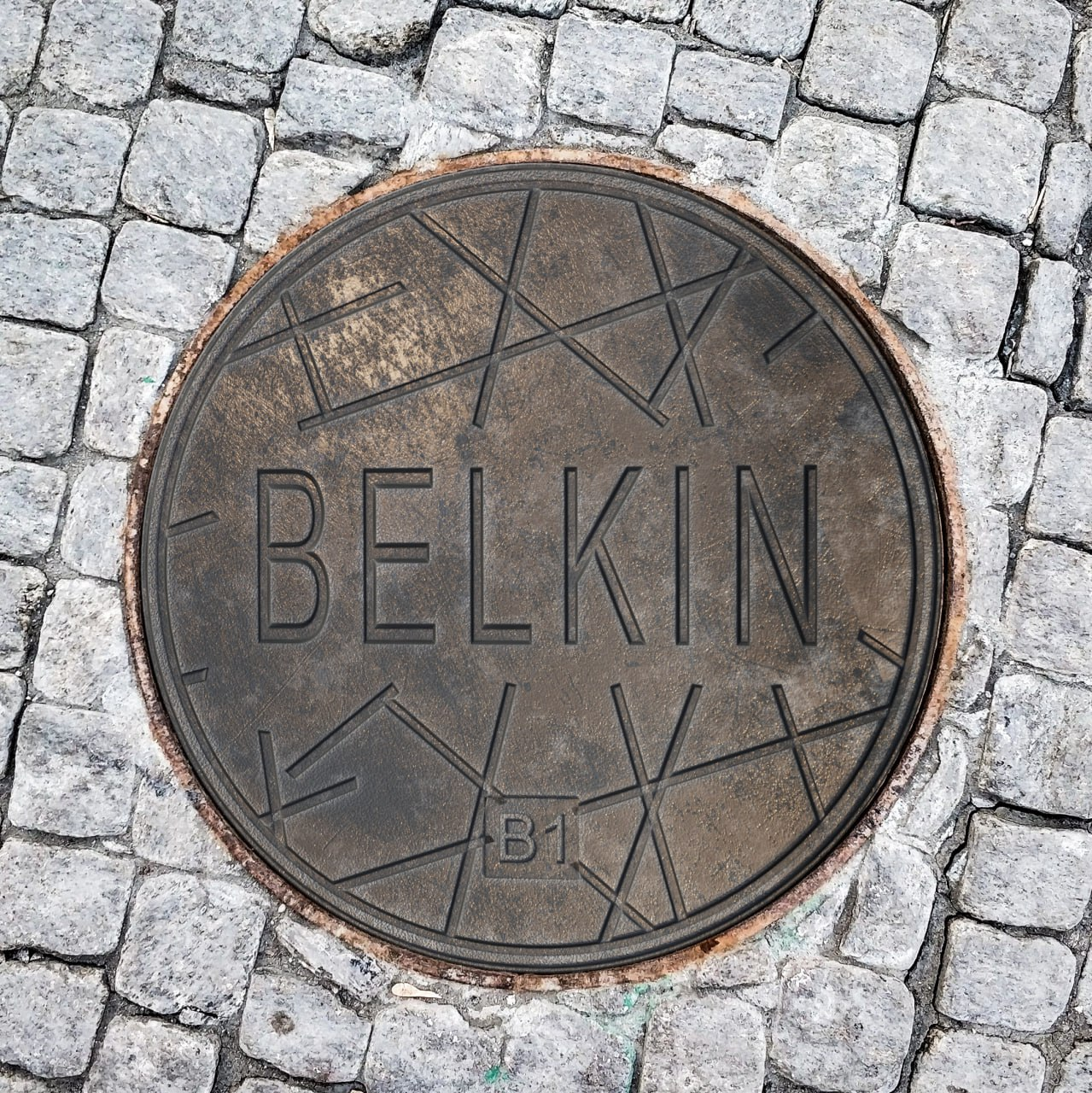 Крышка канализационного люка из чугуна, украшенная надписью «BELKIN»